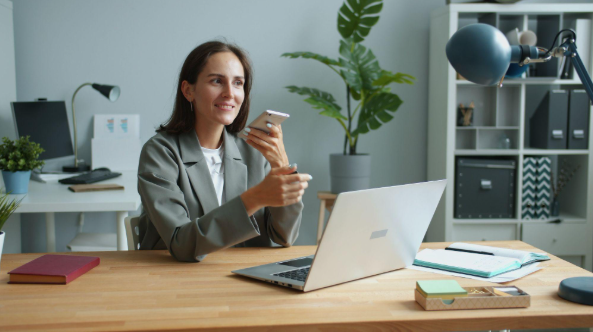 Should Employees Use Personal Devices for Work? The Hidden Risks for NJ Businesses 1 lady holding phone while working on a laptop